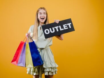 Tjej med shoppingpåsar hållandes en OUTLET-skylt