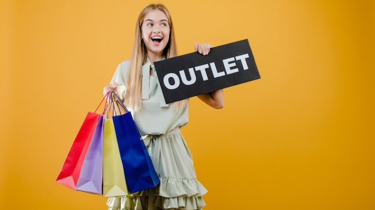 Tjej med shoppingpåsar hållandes en OUTLET-skylt